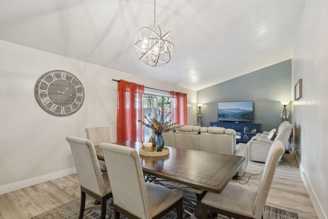 dining room featuring light hardwood / wood-style floors, lofted ceiling, and an inviting chandelier