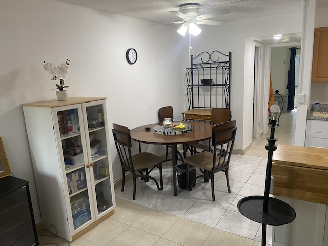 tiled dining space with ceiling fan and a textured ceiling