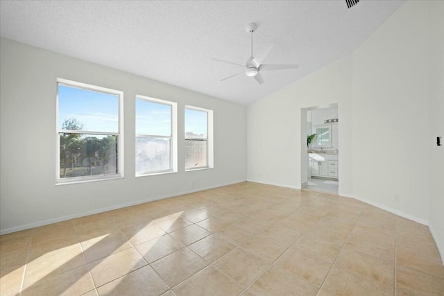 tiled spare room featuring a textured ceiling, ceiling fan, and lofted ceiling