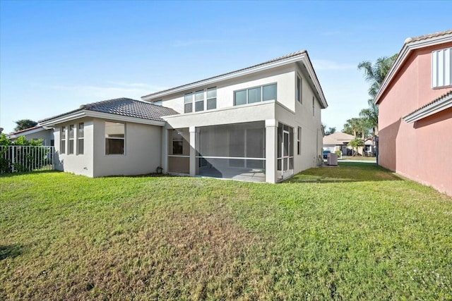 rear view of property featuring a sunroom and a yard