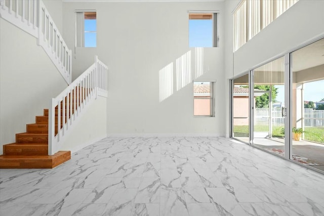 unfurnished living room featuring plenty of natural light and a high ceiling