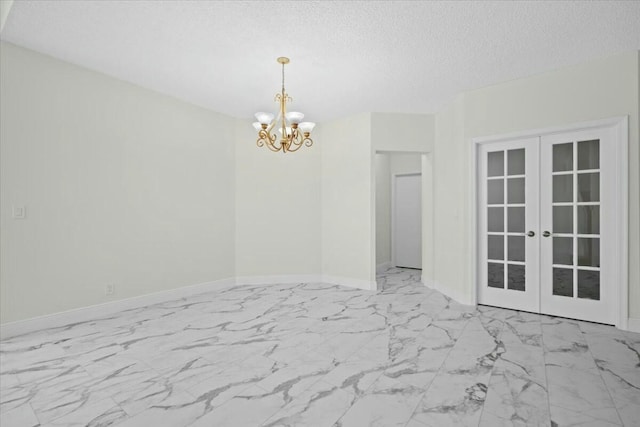 empty room featuring a notable chandelier, a textured ceiling, and french doors