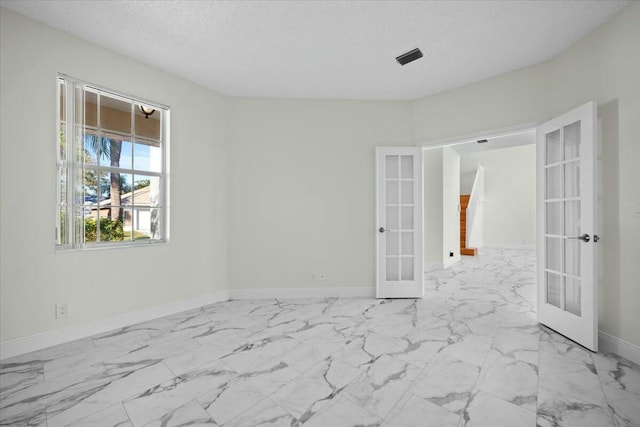 spare room featuring a textured ceiling and french doors