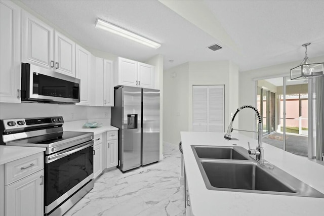 kitchen featuring appliances with stainless steel finishes, white cabinetry, hanging light fixtures, and sink