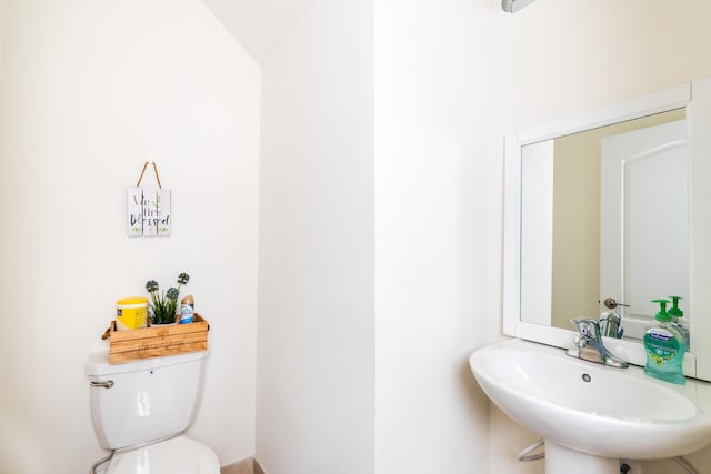 bathroom featuring toilet, sink, and vaulted ceiling