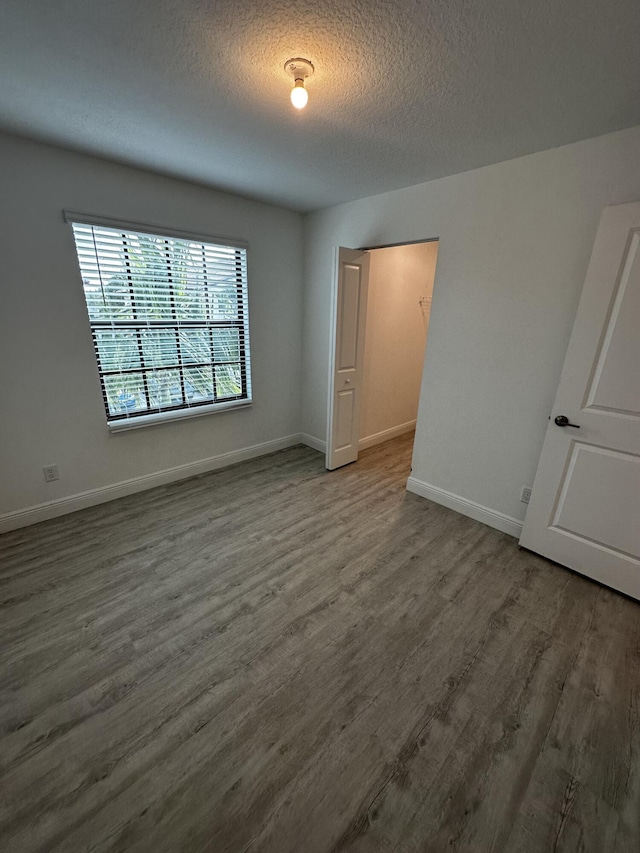 spare room with a textured ceiling and dark wood-type flooring