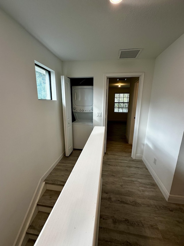 hallway featuring stacked washing maching and dryer and dark hardwood / wood-style floors