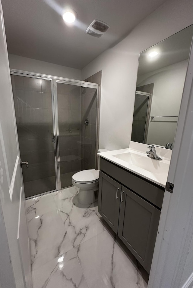 bathroom with vanity, toilet, and a shower with shower door