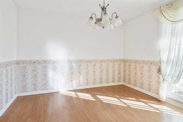 empty room with hardwood / wood-style floors and a notable chandelier