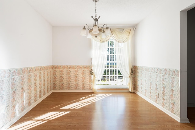 spare room featuring hardwood / wood-style flooring and an inviting chandelier