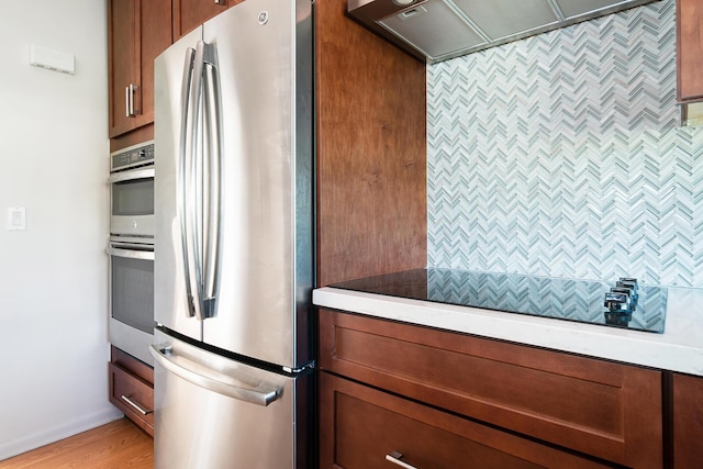 kitchen with ventilation hood, stainless steel fridge, and light hardwood / wood-style flooring