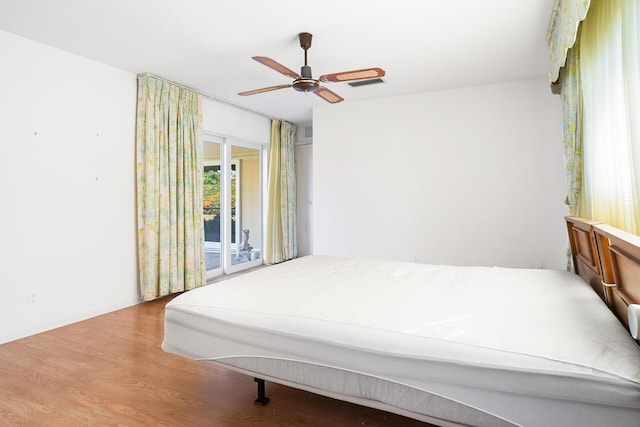 bedroom with access to exterior, hardwood / wood-style flooring, and ceiling fan