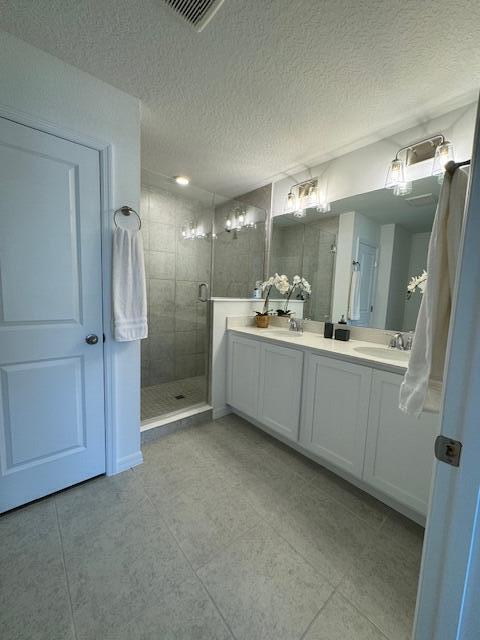 bathroom featuring vanity, a textured ceiling, and a shower with shower door