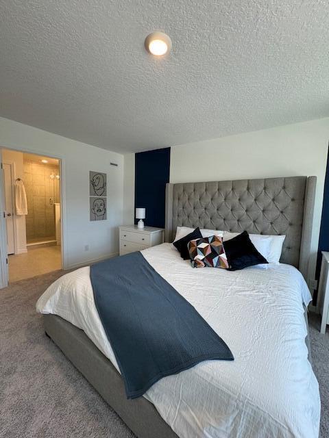 bedroom featuring carpet flooring, ensuite bathroom, and a textured ceiling