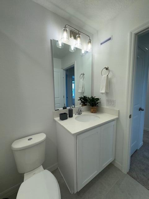 bathroom featuring tile patterned floors, vanity, toilet, and a textured ceiling