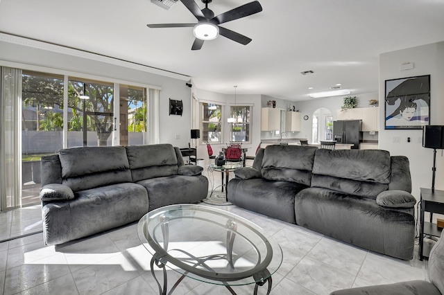 living room featuring a wealth of natural light, sink, and ceiling fan with notable chandelier