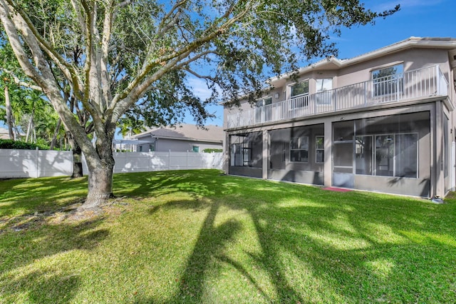 rear view of house featuring a yard and a balcony