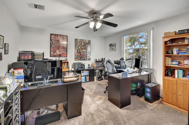 carpeted office space with a textured ceiling and ceiling fan