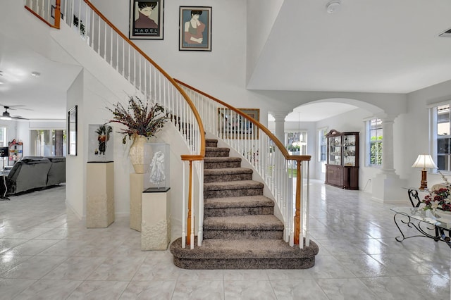 staircase featuring decorative columns, tile patterned floors, a wealth of natural light, and ceiling fan