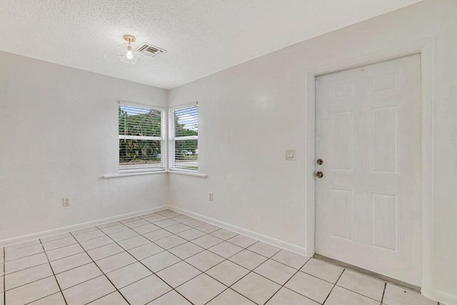 tiled spare room with a textured ceiling