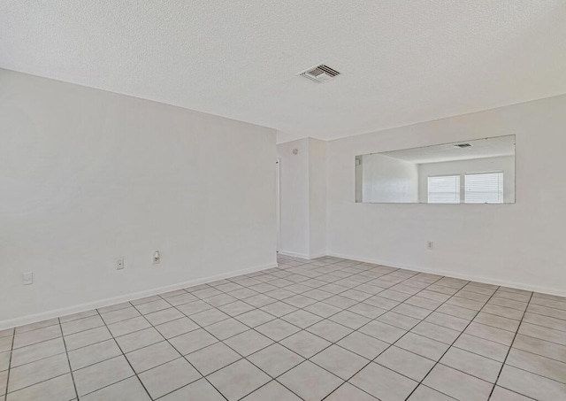 spare room with light tile patterned floors and a textured ceiling