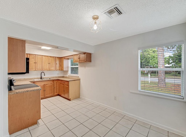 kitchen with sink, stainless steel stove, a textured ceiling, and light tile patterned floors