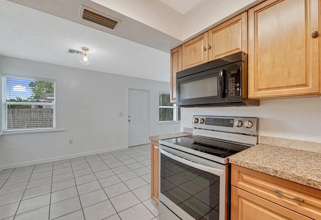 kitchen featuring light tile patterned floors, a textured ceiling, stainless steel electric stove, and light brown cabinets