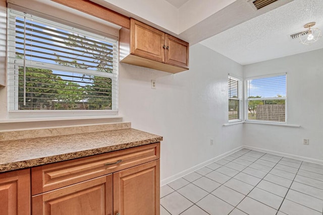 kitchen featuring light tile patterned flooring, a textured ceiling, and a wealth of natural light