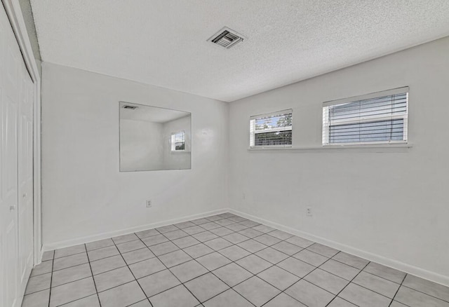 tiled empty room featuring a textured ceiling