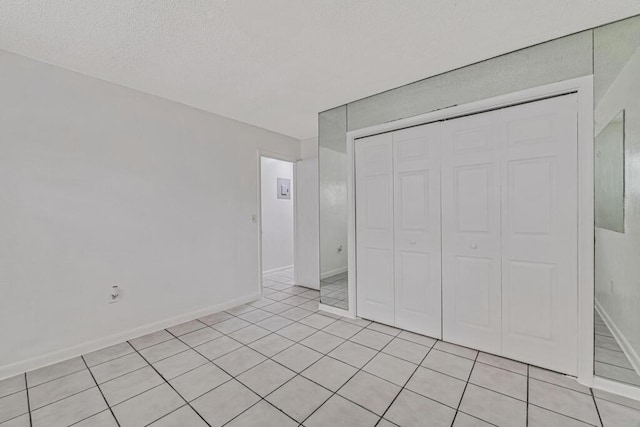 unfurnished bedroom with light tile patterned floors, a textured ceiling, and a closet