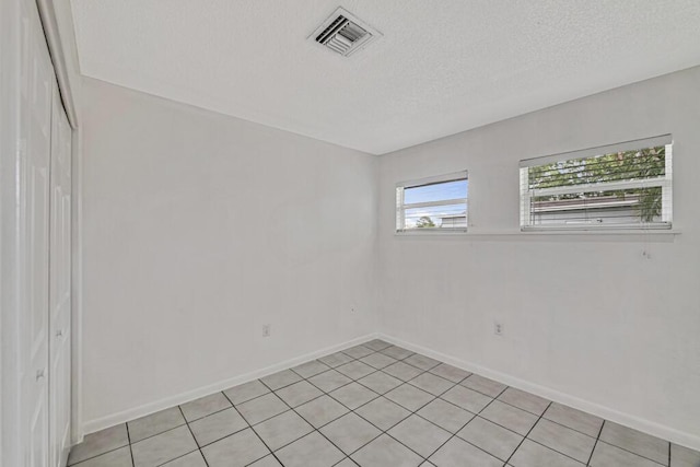 empty room featuring a textured ceiling and light tile patterned flooring