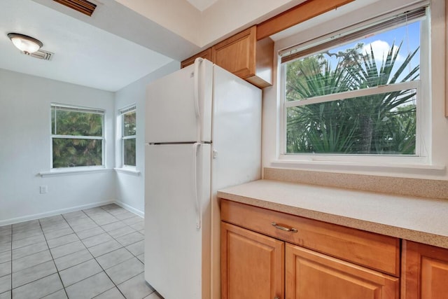 kitchen featuring plenty of natural light, light tile patterned floors, and white refrigerator