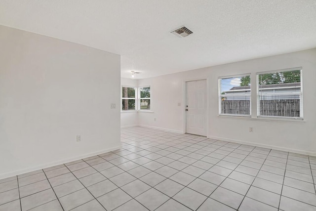 spare room with light tile patterned floors and a textured ceiling