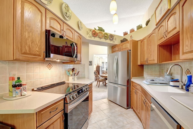 kitchen featuring light tile patterned floors, light countertops, appliances with stainless steel finishes, a sink, and a textured ceiling