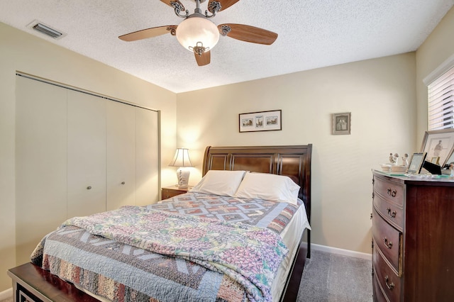 bedroom featuring visible vents, a ceiling fan, a textured ceiling, dark carpet, and a closet