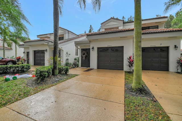 view of front of home featuring a garage, driveway, a tile roof, and stucco siding