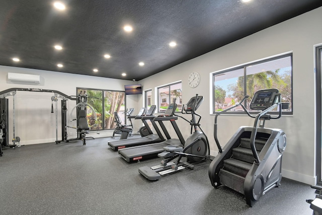 workout area featuring recessed lighting, a wall mounted air conditioner, a textured ceiling, and baseboards