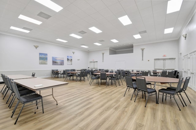 dining space with a paneled ceiling, a towering ceiling, and light wood finished floors