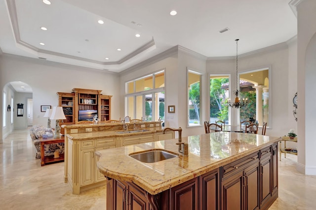 kitchen with a center island with sink, a notable chandelier, sink, and decorative light fixtures