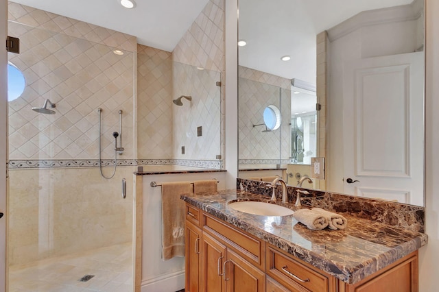 bathroom featuring a shower with door and vanity