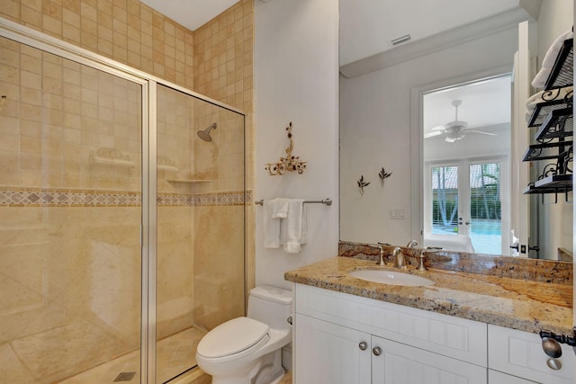 bathroom featuring ceiling fan, a shower with door, vanity, and toilet