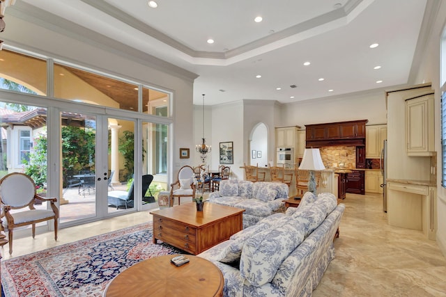 living room with a raised ceiling, ornamental molding, and french doors