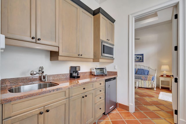 kitchen with light stone counters, sink, light tile patterned floors, and stainless steel appliances