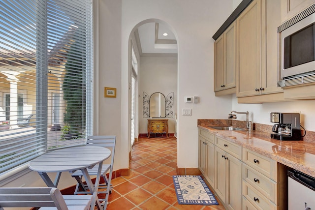 kitchen featuring a healthy amount of sunlight, stainless steel microwave, sink, and cream cabinets