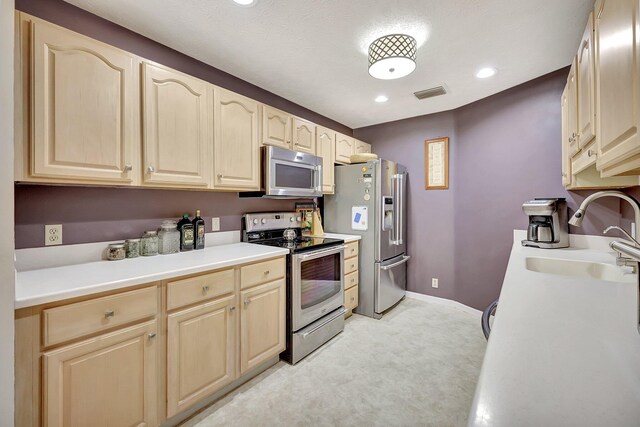 8865 SE May Ter, Hobe Sound, FL 33455 - kitchen featuring stainless steel appliances, a sink, light brown cabinetry, light carpet, and light countertops