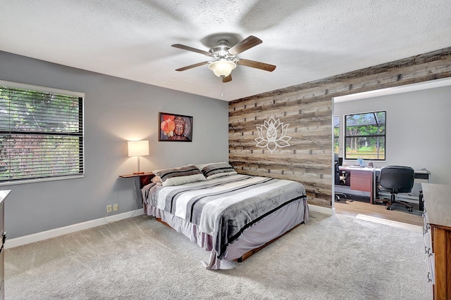 carpeted bedroom with a textured ceiling, ceiling fan, and wooden walls