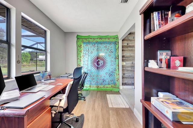 office space featuring visible vents, baseboards, wood finished floors, and wood walls