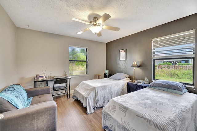 bedroom featuring ceiling fan, light hardwood / wood-style flooring, and a textured ceiling