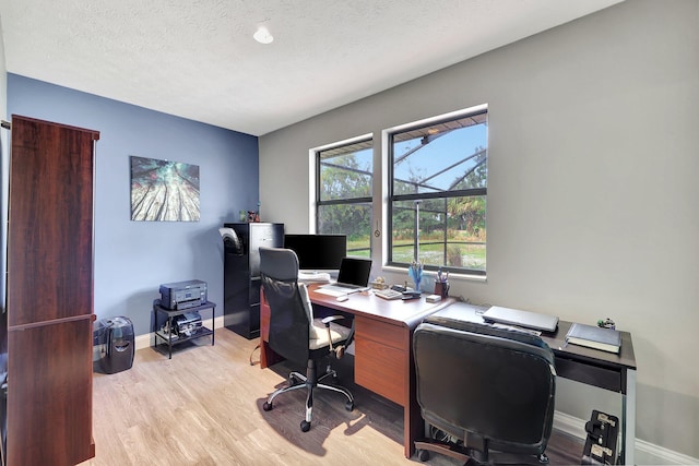 office featuring light wood-style floors, a textured ceiling, and baseboards