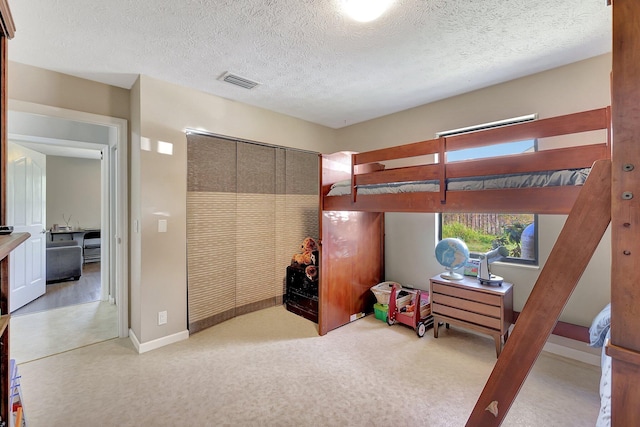 carpeted bedroom with a textured ceiling and a closet